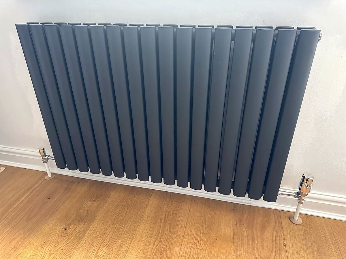 Anthracite oval-column radiator on a wood floor